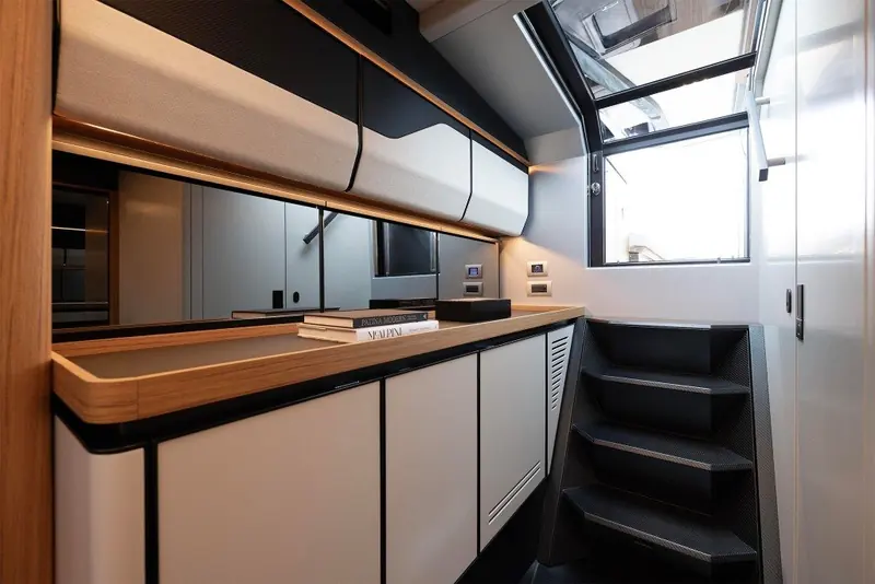 A compact galley finished in dark wood and matte panels tucks into the companionway, enough to support a weekend aboard rather than day trips only.