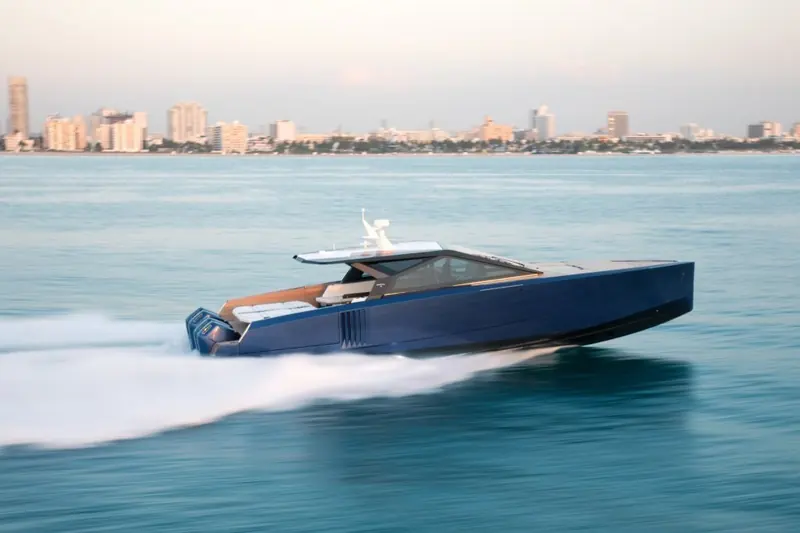 Running at speed off Miami Beach, the dark blue hull and low hardtop set against a motion-blurred skyline.