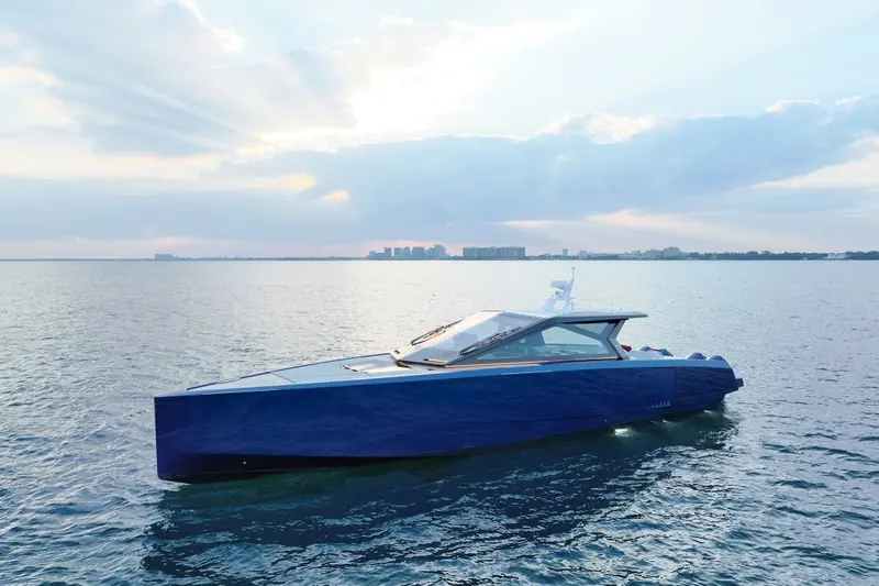 At rest on flat water with the Miami skyline behind, the low-slung profile and open cockpit visible end to end.