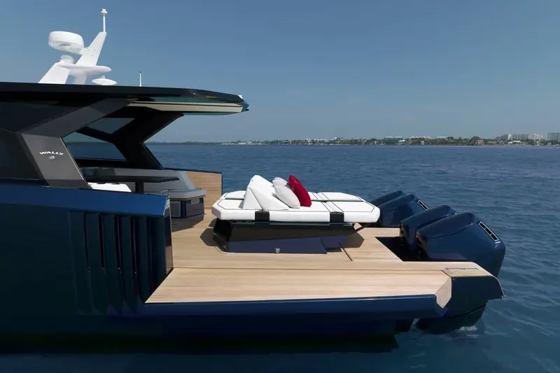 Aft lounge deck close up, white cushions against the dark hull with the outboard engines and skyline in the background.