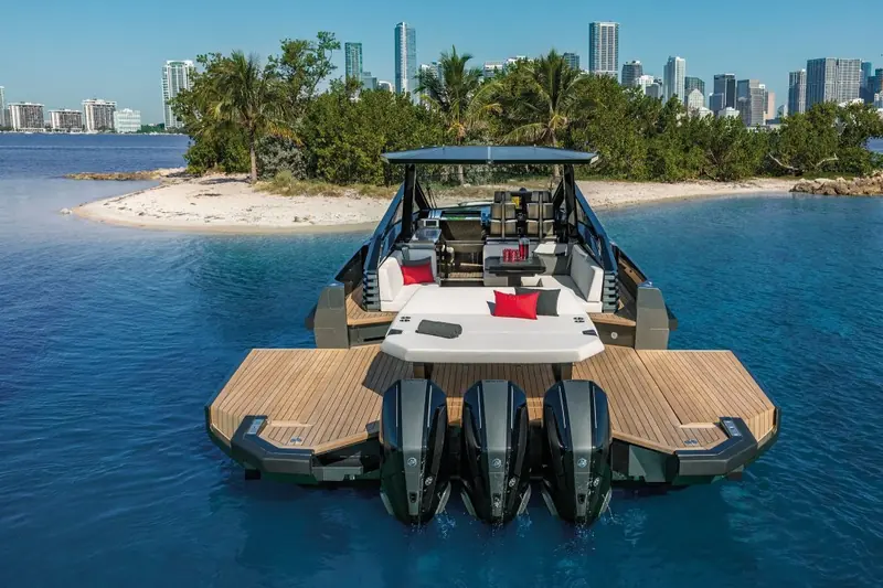 Anchored off a private sandy island with guests aboard, the swim platform down and cushions arranged for a beach stop.