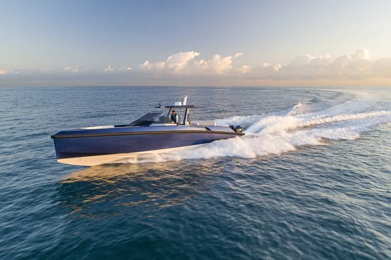 Underway at sunrise, the helmsman at the wheel under the T-top and a broad, symmetrical wake trailing astern.