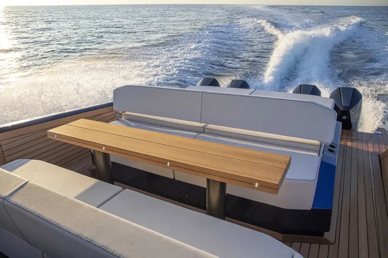 Stern-on at anchor, the teak swim platform bridging the gap between the twin outboard mounts.
