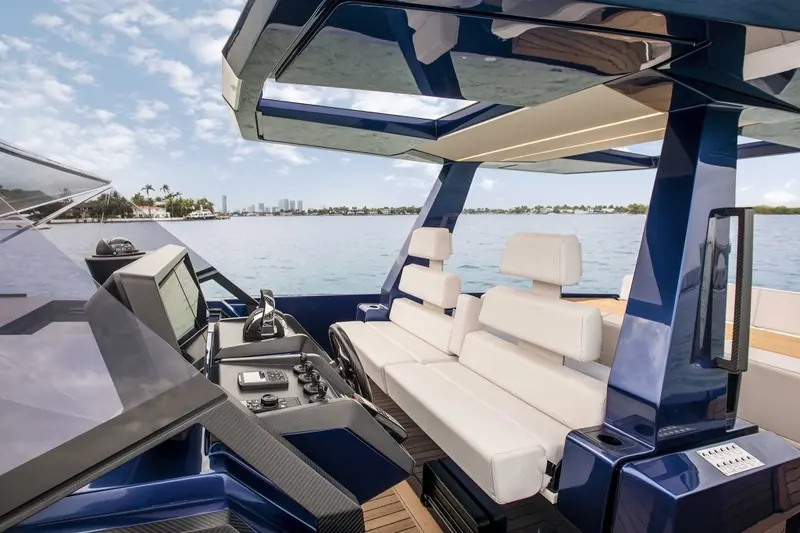 Helm station and instrument binnacle under the hardtop, with the Miami skyline visible through the windscreen.