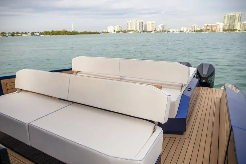 Anchored beside a private sandbar island, teak platform down and the aft lounge cushions arranged for a beach stop.
