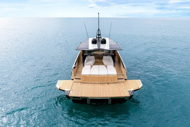 Stern-on with the hydraulic tender platform lowered to the water, teak swim steps either side of the transom.