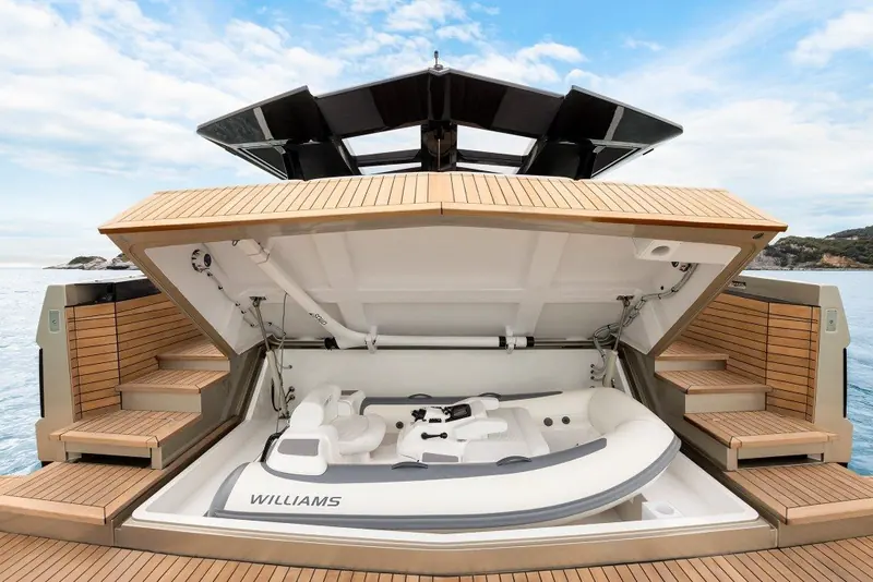 Transom garage raised to reveal a Williams jet tender stowed in its own teak-lined bay.