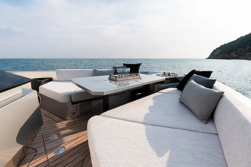 Aft cockpit dining table set with glassware for guests, open water and a headland visible beyond the coaming.