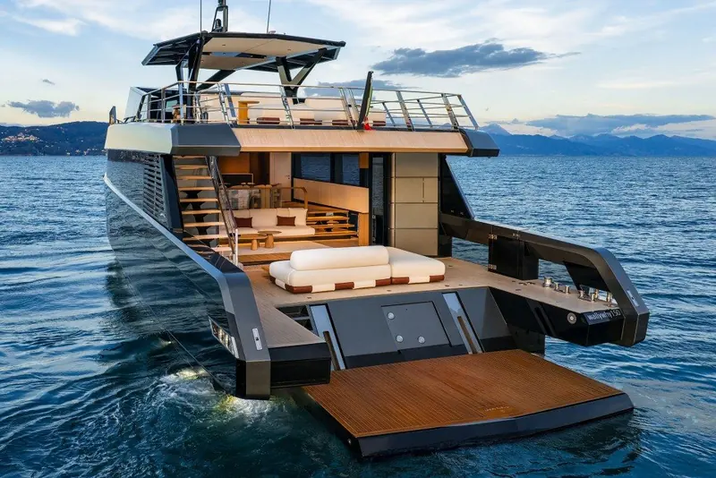 Transom garage open with a Williams jet tender stowed inside, teak side decks and folding steps either side of the bay.
