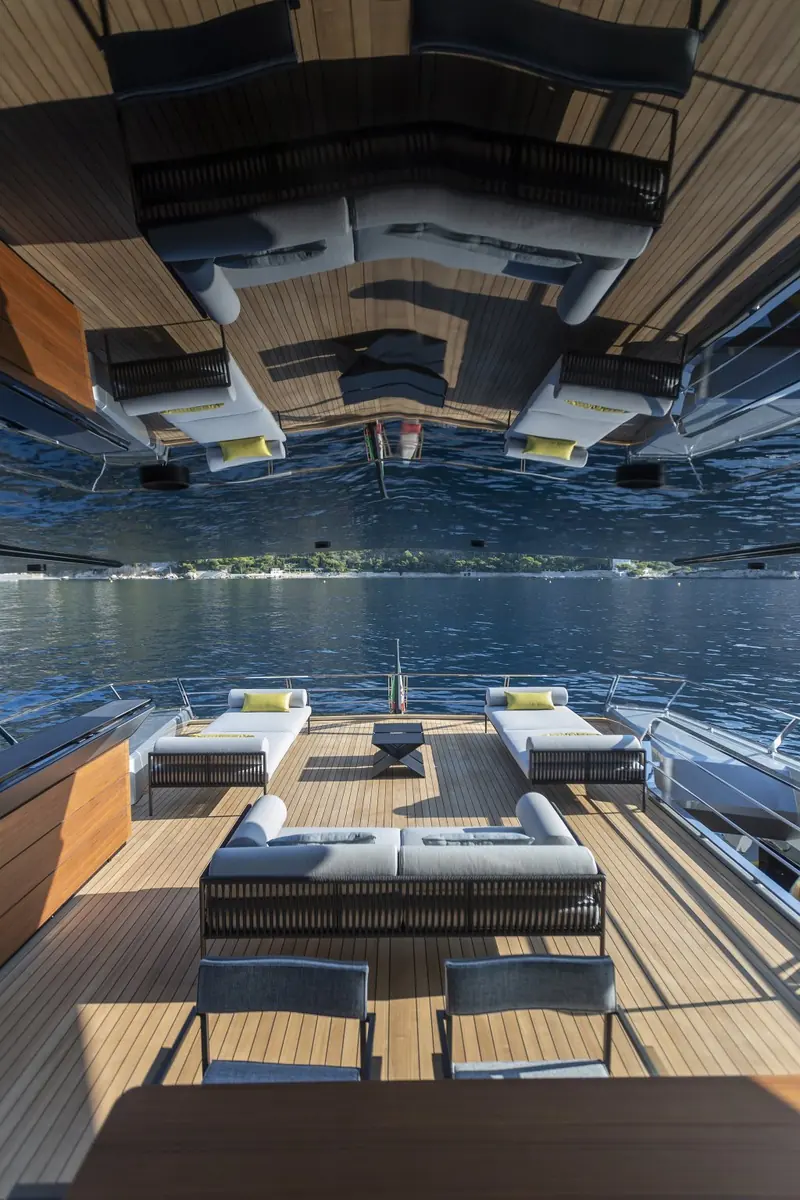 The aft cockpit lounge seen from directly above, cushioned bench seating wrapped around a low table under the raised transom door.