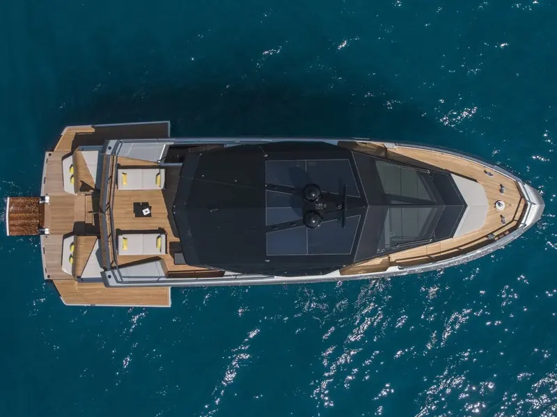 Overhead as she comes about, the full deck plan visible from the foredeck sunpad back to the open transom garage.