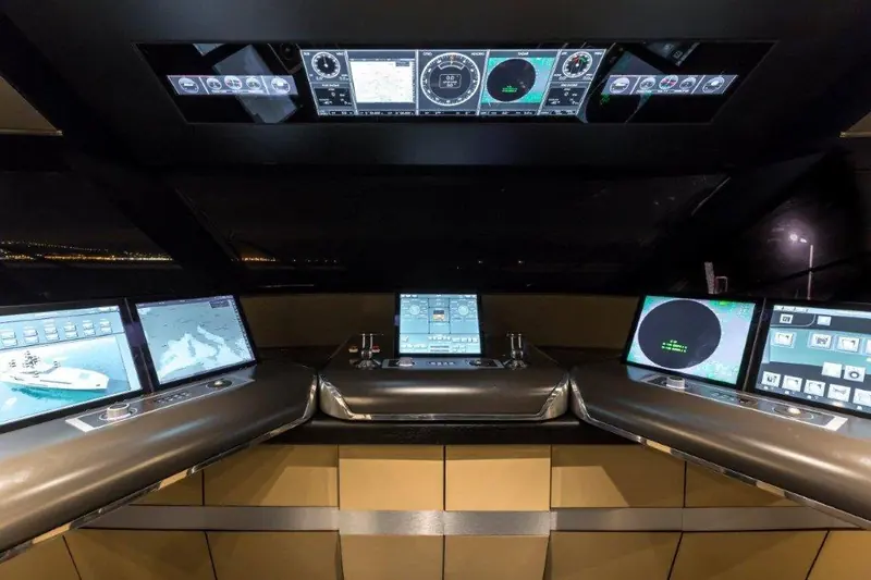 Genesi's wheelhouse, with the yacht's own night-running lights reflected on the console screens.