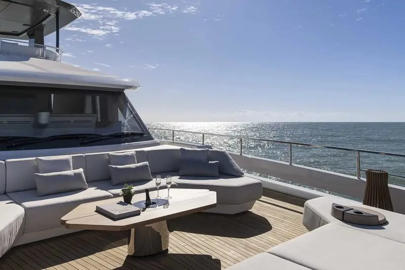 Upper deck seating looking aft, glass railings keeping the sightline to the water open from the sofa.