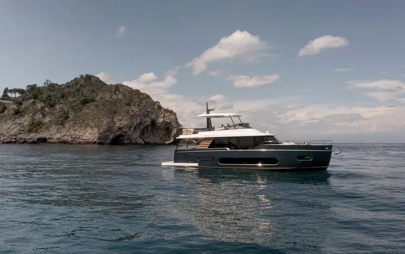 At anchor off a rocky headland near Taormina, the Magellano 60 shows off Ken Freivokh's vertical-windowed profile and the low-slung aft deck.