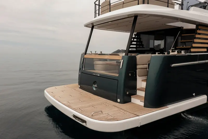 The swim platform and transom door, marked MAGELLANO 60, with the teak-slatted boarding stair leading up to the cockpit.