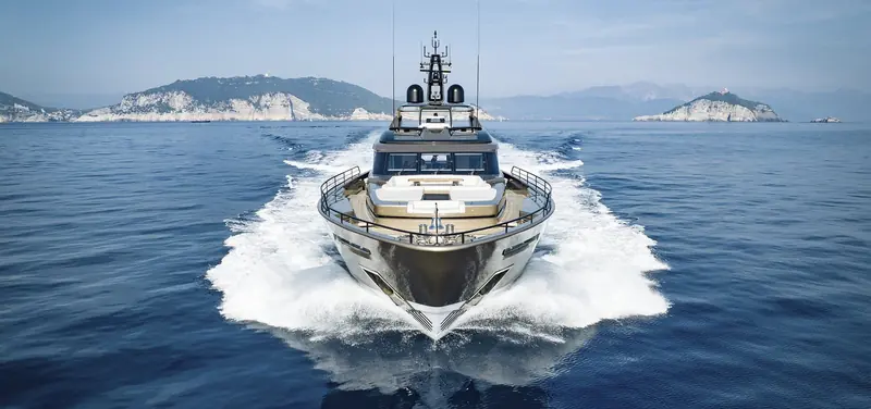 The Superfast 42 driven bow-on at full chat, twin bow rails and forward sunpad framed by the wake as her topsides throw spray wide, headland islands fading into haze either side of the bow.