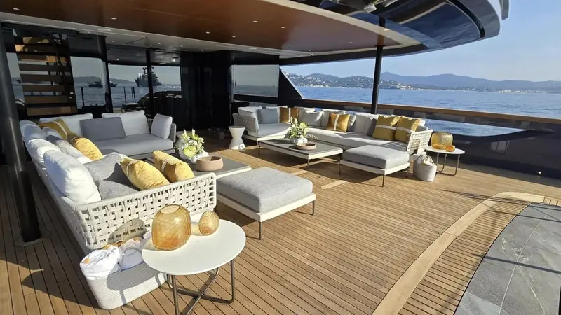 Akula's aft deck lounge laid out for guests, with St Tropez and the hills of the Var visible off the stern.