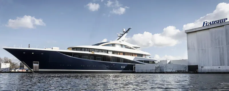 Faith alongside at the Feadship yard on delivery day, the yard's own sign in the frame behind her.