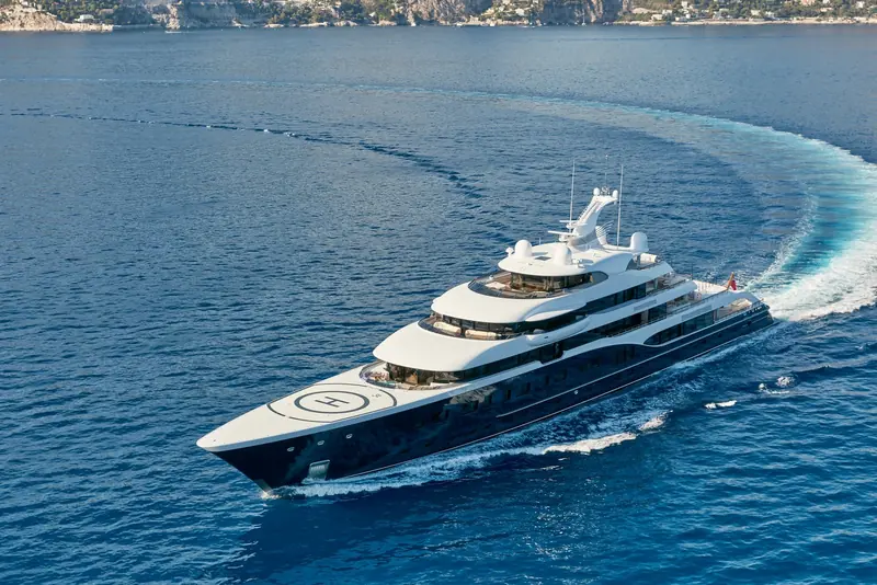 The same stretch of coast from directly overhead, the wake curving hard as she comes off a turn past Cap Ferrat.