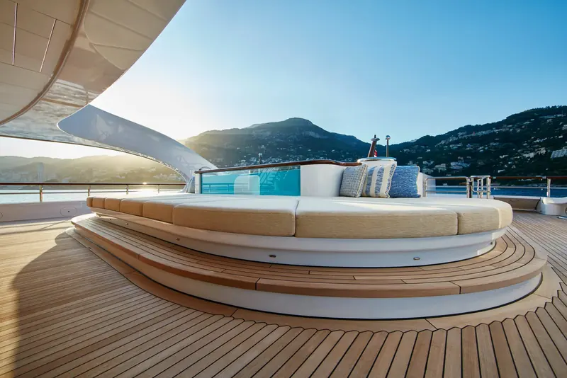 A curved aft-deck daybed with its own glass viewing panel into the pool below, Villefranche-sur-Mer behind.