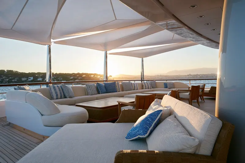 The covered aft lounge at sunset, deep sectional seating under a retractable canopy.