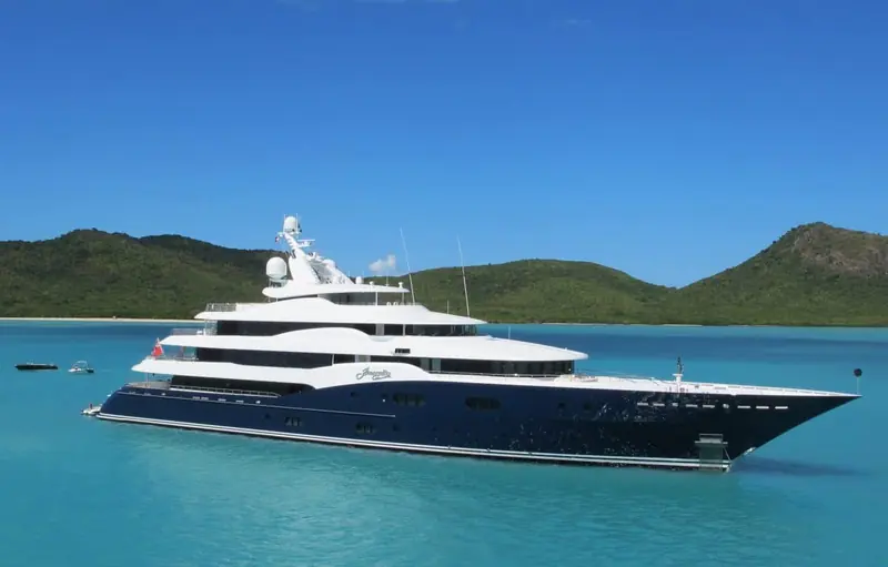 Amaryllis at anchor off a tropical island, her name lettered in script across the dark blue bow.