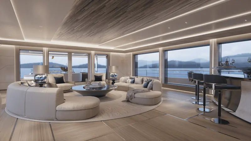 The main-deck salon and bar, finished in pale sycamore with a backlit onyx-look ceiling panel; the wraparound glazing keeps the horizon in view from every seat.