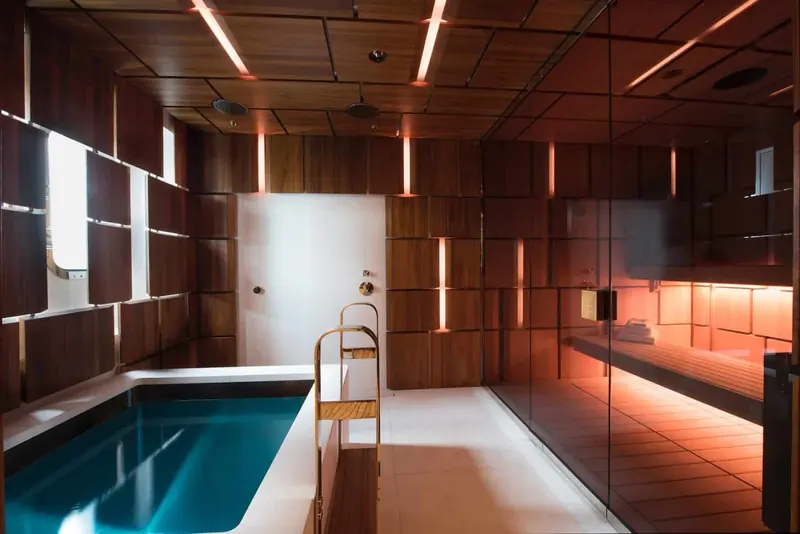 The onboard spa: a wood-lined sauna opening straight onto a small plunge pool, built for warming up after a landing on the ice.