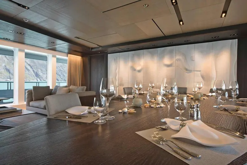 The formal dining room, floor-to-ceiling glazing turning every meal into a view of the mountains outside.