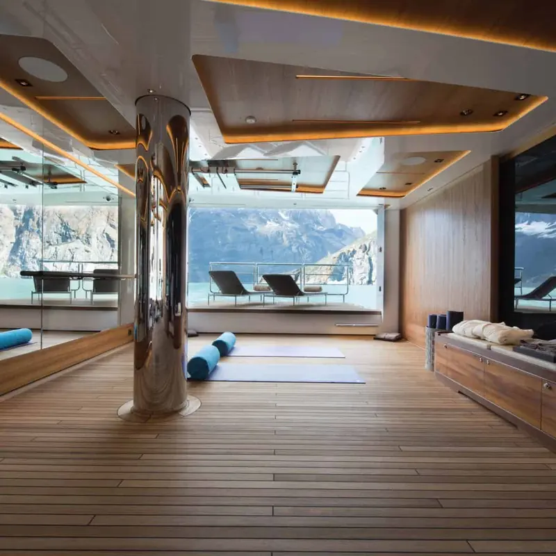 The gym, its mirrored ceiling column doubling the space and framing the fjord walls through the windows.