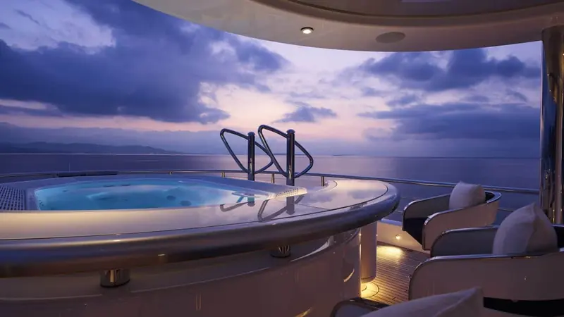 The Jacuzzi deck at dusk, its glass balustrade left uninterrupted so the pool appears to run to the horizon.
