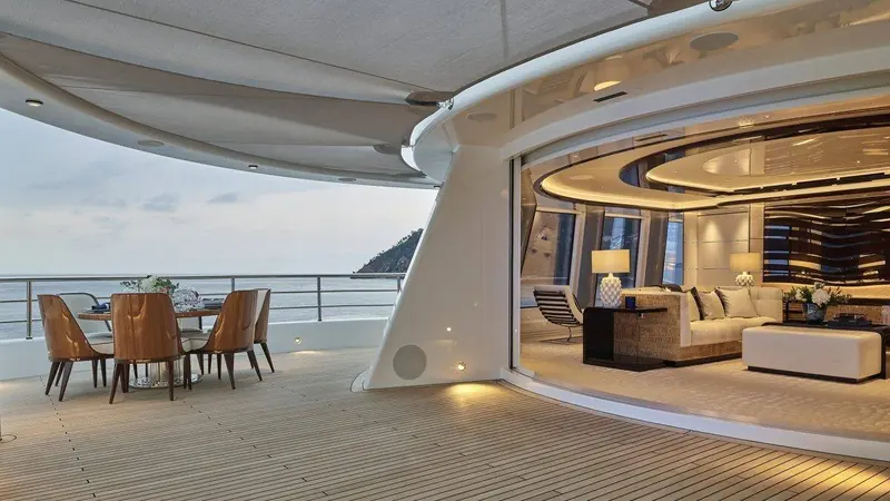 Aft deck dining under a sculpted overhang, open on two sides to the water.
