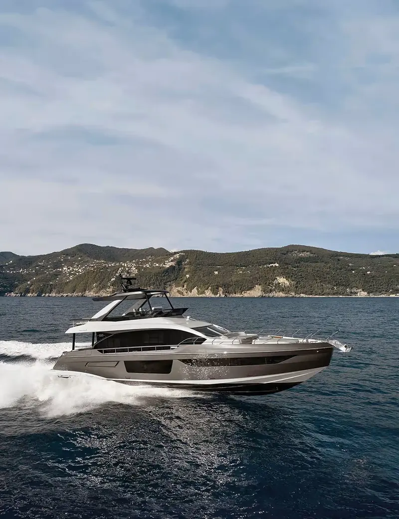 Azimut Fly 68 running along the Ligurian coast, the hard-top flybridge and hull-side glazing that mark Azimut's current Fly range visible in profile.