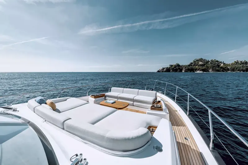 Foredeck sunpad and lounge seating, angled to face aft and forward alike, shaded by a fold-out awning off the flybridge.