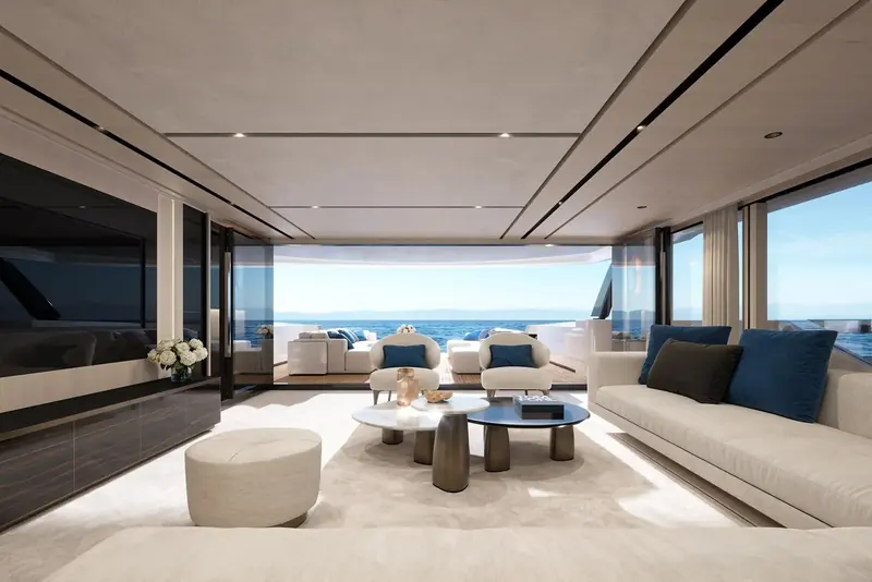 The main-deck salon, kept low on furniture height so the window line reads uninterrupted from the seating, with the sea visible on both sides of the room at once.