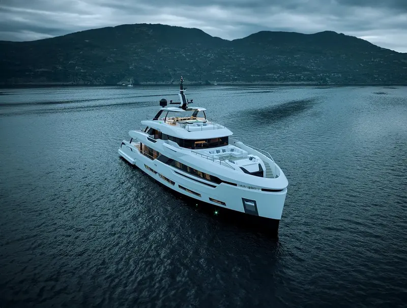 At anchor beneath forested hills, the hull's dark boot-top stripe and the sculpted black window band the two graphic elements that carry the DOM133's profile from a distance.