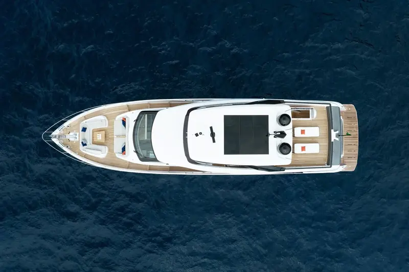 A drone view straight down shows the full deck plan: forward sunpad and seating, a sliding sunroof over the wheelhouse, and a flybridge laid out for sun and dining aft.