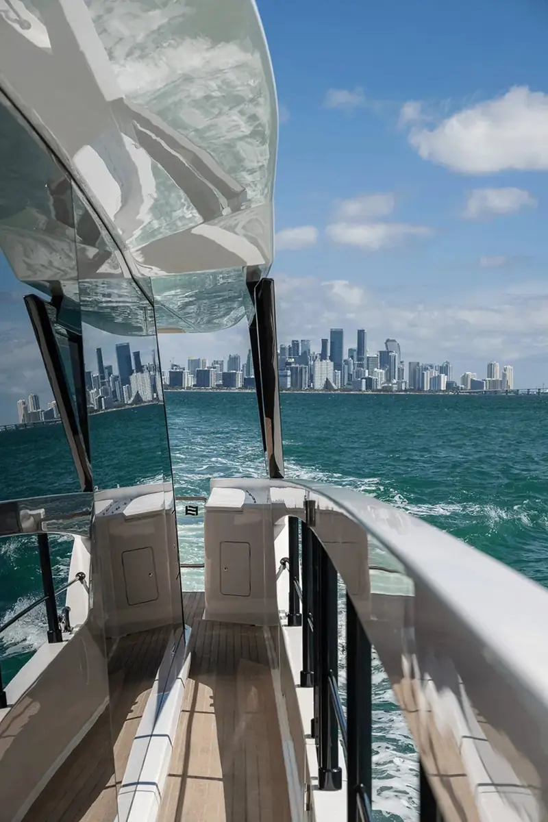 Looking astern from the swim platform toward the Miami skyline, with the transom's boarding ladder and tender-launch space visible either side of the cockpit.