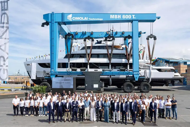 The build and launch team pose for a group photograph in front of the travel lift and the hull.