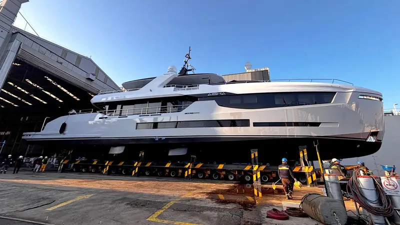 A three-quarter view on the transport trailer shows the low freeboard and long foredeck that give Aisha her shallow-draught profile.