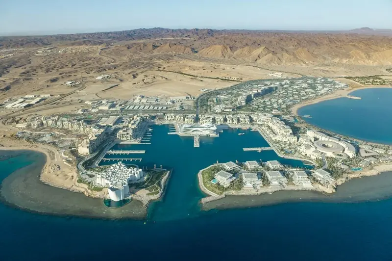 AMAALA Marina Village from the air, with the yacht club at the head of the basin and the Hijaz Mountains behind