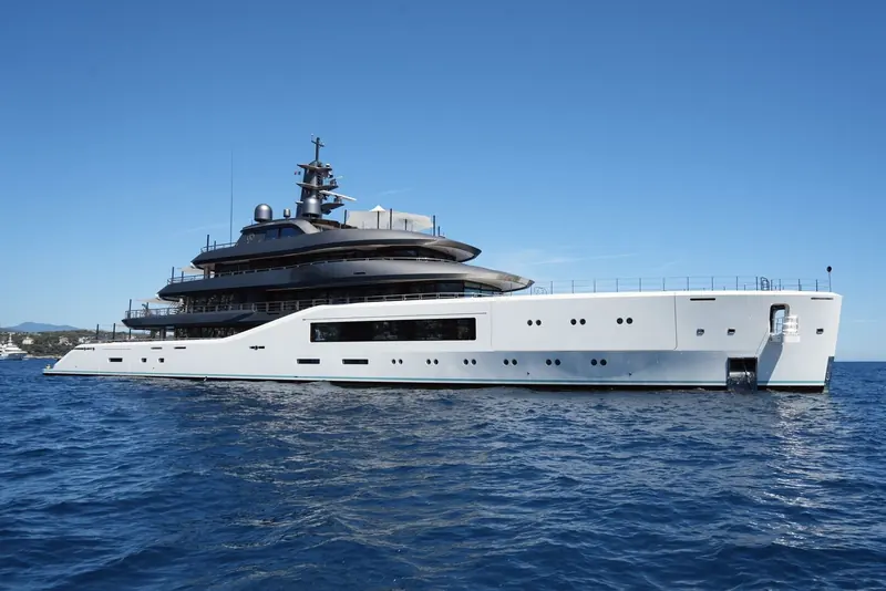 Pangea rides at anchor off the French Riviera, her raised open-deck bridge structure and matt-dark upperworks set against a plain white hull below the waterline stripe.