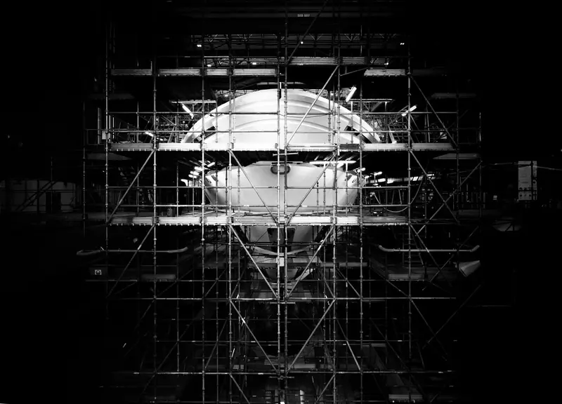 The bow takes shape under scaffolding during construction, the bulbous underwater form visible before the superstructure closed in around it.