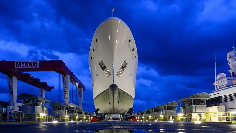A hull stands under the yard's travel lift at night, part of infrastructure that can haul yachts up to 95 metres on the 4,000 tonne ShipLift.