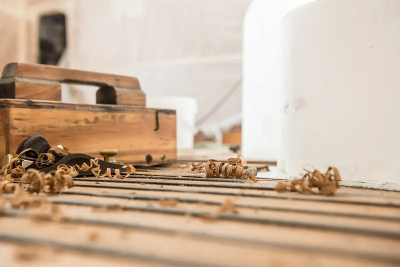 Wood shavings on a workbench during joinery work for a refit, one of the in-house carpentry skills the yard keeps on site rather than outsourcing.