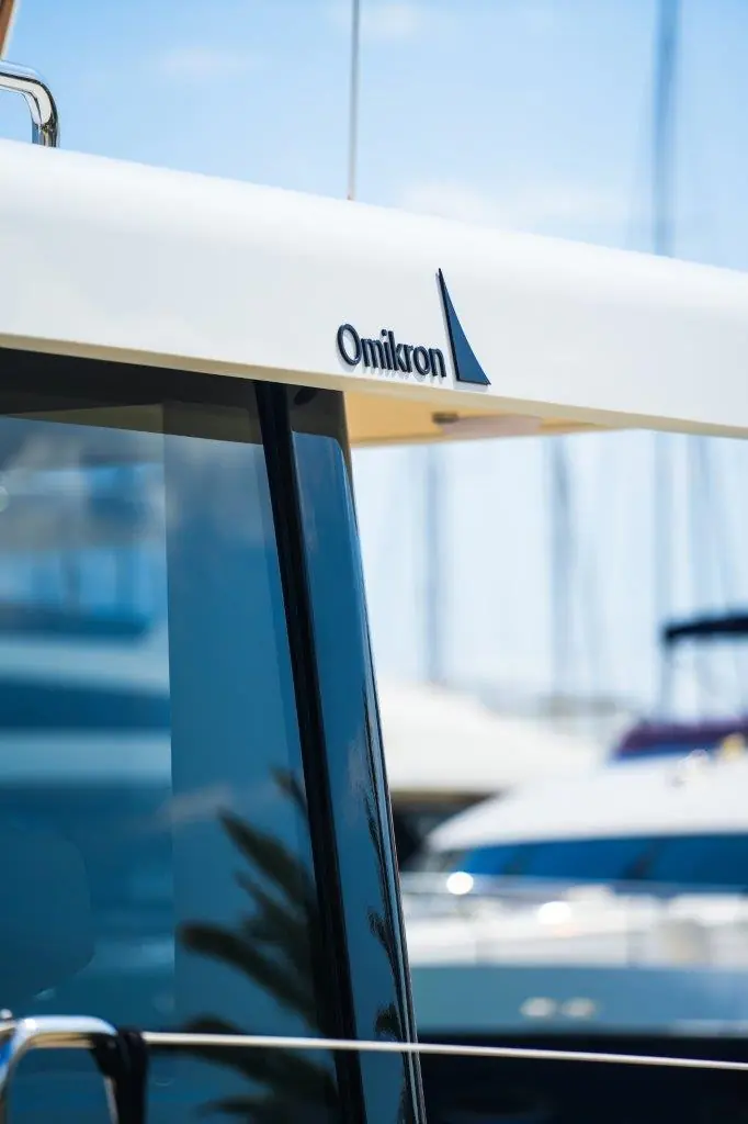 The Omikron badge. The yard's chairman says the owner's offshore racing on the unrelated training yacht Aiolos is deliberate research for Argo 54, not a marketing exercise.