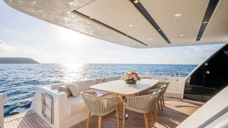 The aft deck dining table, set for eight under the hardtop, with the swim platform astern.