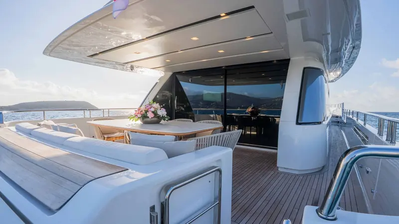 The aft deck opens straight into the main salon through full-height glass doors.