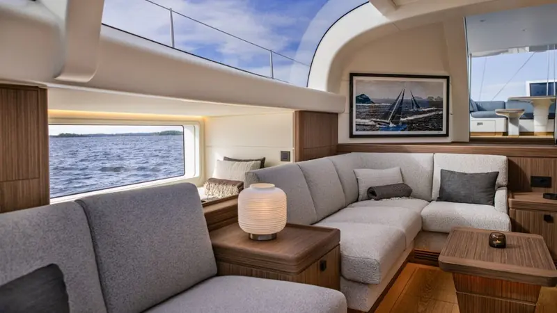 The saloon, designed by Adam Lay Studio, uses brushed walnut and textured veneers worked to suggest water ripples, with full-height glazing over the waterline.
