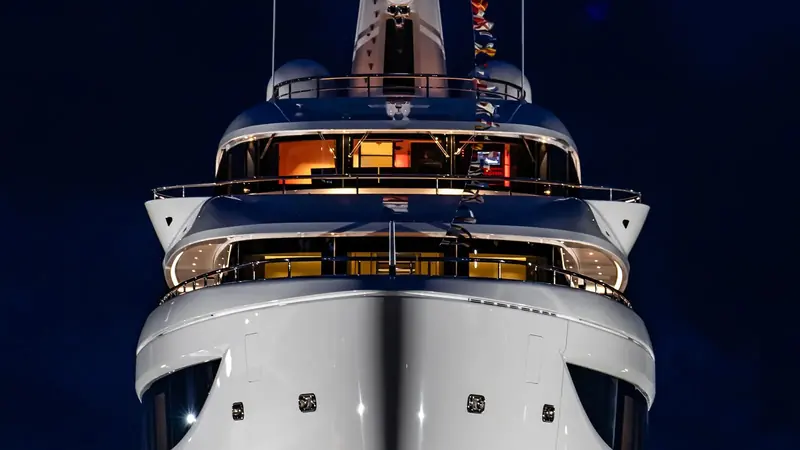 A close bow view at night shows the launch lighting rig and the yacht's raked stem, RWD's exterior styling shared with Symmetry.
